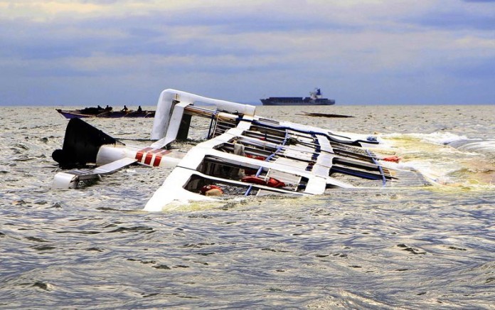 A fishing boat passes the Super Shuttle Ferry 7 which capsized in strong winds and huge waves unleashed by Typhoon Kalmaegi, locally named Luis, in Manila Bay