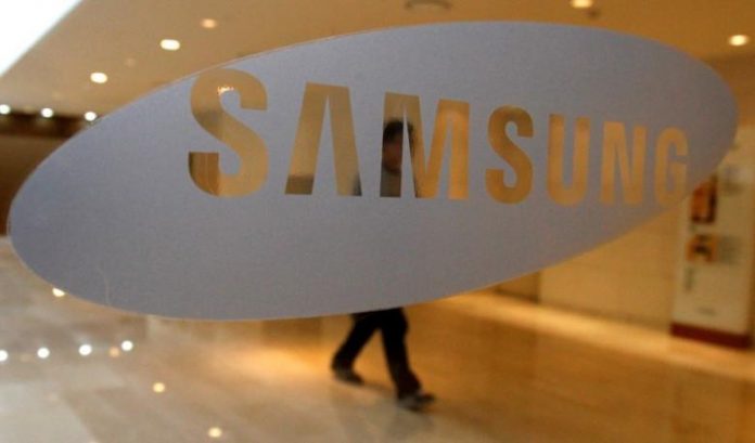 A man walks behind a logo of Samsung Electronics at the company's headquarters in Seoul